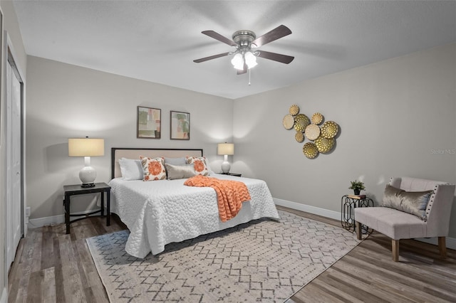 bedroom featuring a closet, ceiling fan, baseboards, and wood finished floors