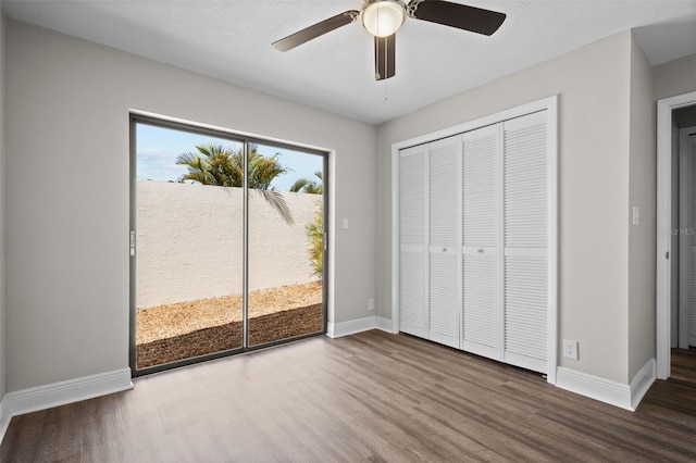 unfurnished bedroom featuring wood finished floors, a ceiling fan, baseboards, access to exterior, and a closet