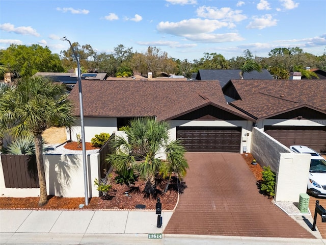 single story home featuring driveway, an attached garage, fence, and stucco siding