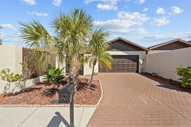 view of front of home with a garage, fence, decorative driveway, and stucco siding