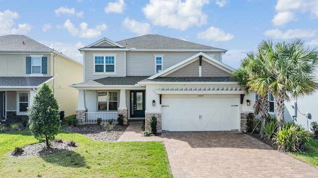 craftsman-style home featuring covered porch, a front lawn, decorative driveway, and a garage