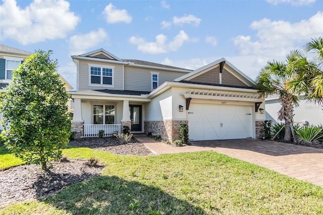 craftsman-style home featuring decorative driveway, covered porch, a garage, stone siding, and a front lawn