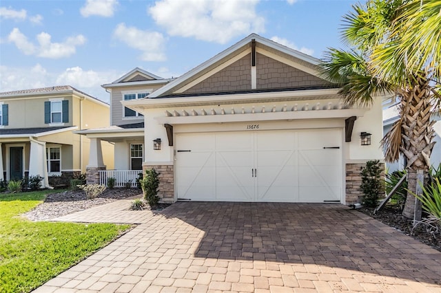 view of front of house with stone siding, decorative driveway, an attached garage, and stucco siding