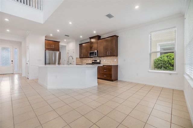 kitchen featuring a center island with sink, crown molding, stainless steel appliances, light countertops, and visible vents