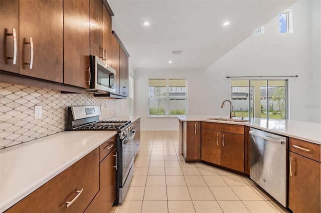 kitchen with light tile patterned floors, a sink, light countertops, appliances with stainless steel finishes, and decorative backsplash