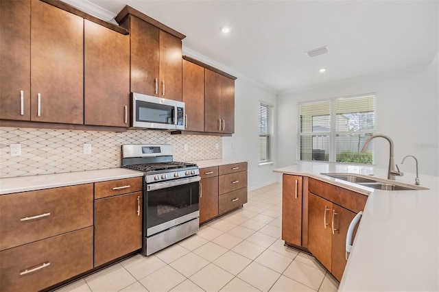 kitchen with tasteful backsplash, ornamental molding, stainless steel appliances, light countertops, and a sink