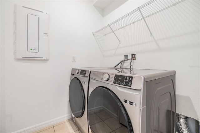 clothes washing area featuring washing machine and dryer, laundry area, light tile patterned flooring, and baseboards