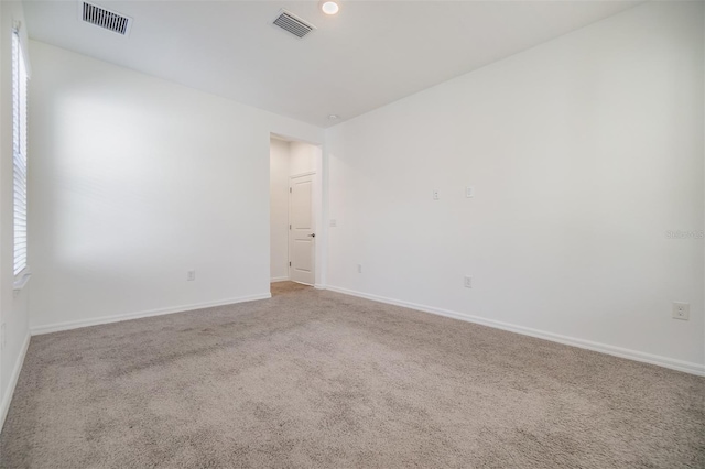 unfurnished room featuring baseboards, visible vents, and light colored carpet