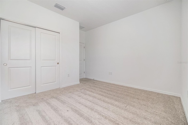 unfurnished bedroom featuring light colored carpet, a closet, visible vents, and baseboards