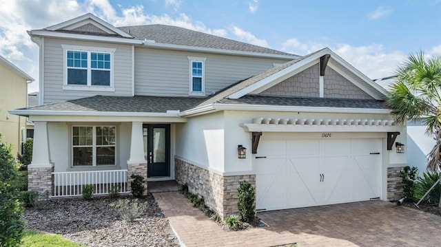 craftsman-style house with a shingled roof, stone siding, and an attached garage