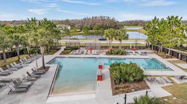 pool featuring a water view, a patio area, and fence