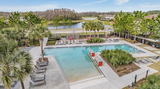 pool with a patio area, a water view, and fence