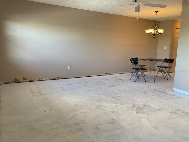 unfurnished dining area featuring concrete floors and ceiling fan with notable chandelier