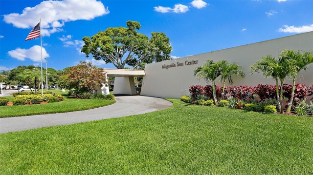 view of front facade with stucco siding, driveway, a carport, and a front yard