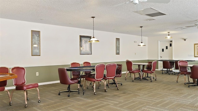 carpeted dining room featuring a community bar, a textured ceiling, baseboards, and a ceiling fan