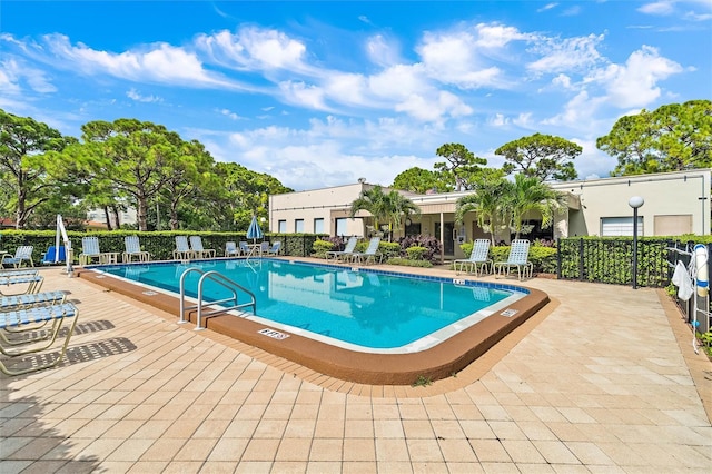 pool with a patio and fence