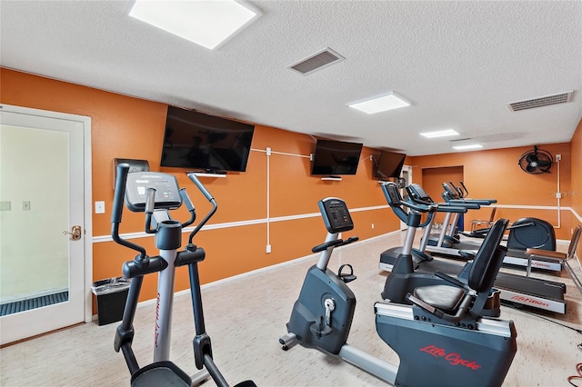 workout area with visible vents, a textured ceiling, and baseboards