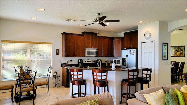 kitchen with arched walkways, visible vents, appliances with stainless steel finishes, open floor plan, and a kitchen breakfast bar