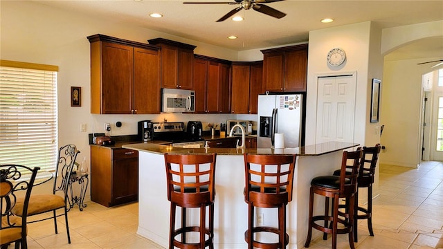 kitchen with stainless steel appliances, arched walkways, ceiling fan, and a breakfast bar