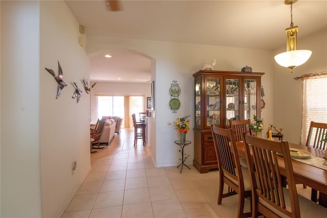 dining area with light tile patterned floors, baseboards, arched walkways, and recessed lighting