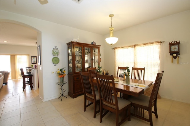 dining room featuring light tile patterned floors, baseboards, and arched walkways