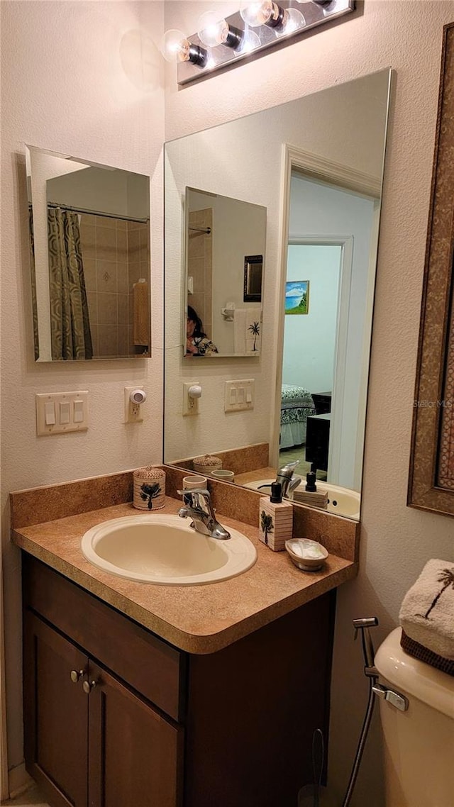 bathroom with a textured wall, vanity, and toilet