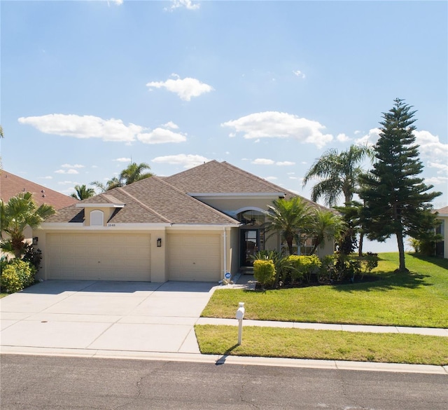 view of front facade featuring stucco siding, a shingled roof, an attached garage, a front yard, and driveway