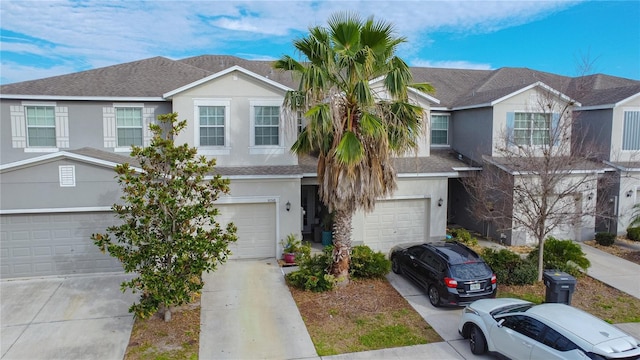 multi unit property with an attached garage, roof with shingles, concrete driveway, and stucco siding