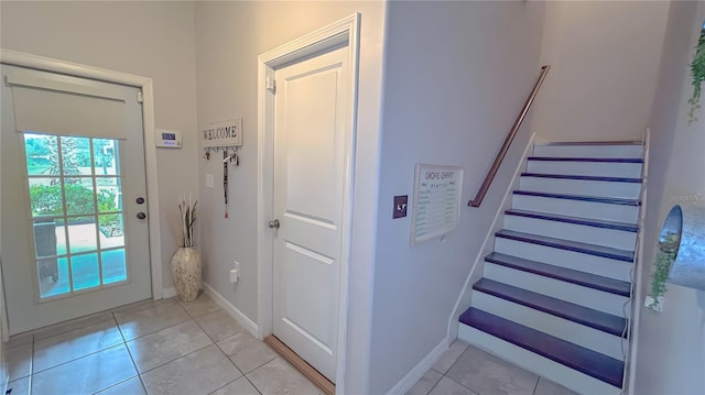 entryway featuring light tile patterned floors, stairs, and baseboards