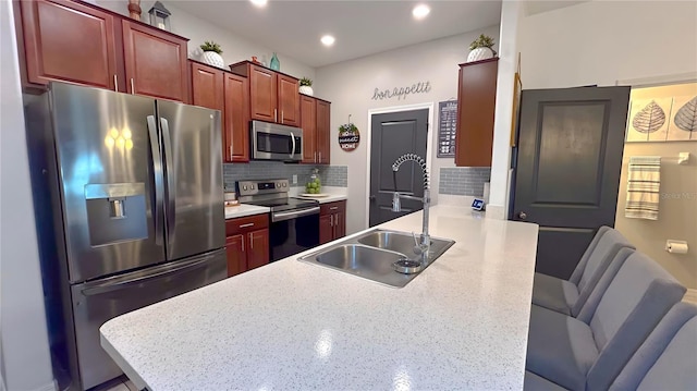 kitchen featuring stainless steel appliances, decorative backsplash, a sink, a peninsula, and a kitchen breakfast bar