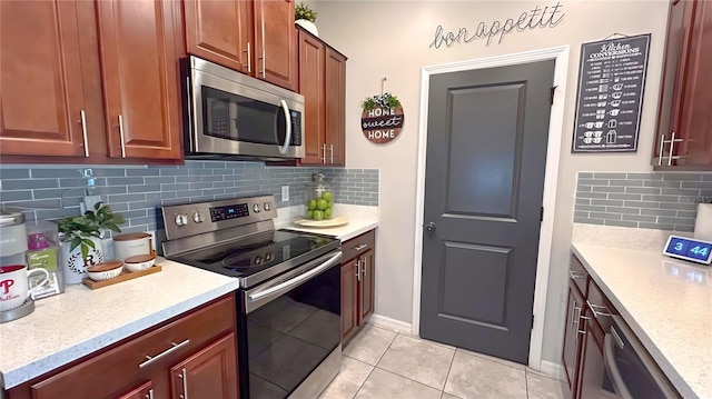 kitchen with light tile patterned floors, baseboards, decorative backsplash, appliances with stainless steel finishes, and light stone counters