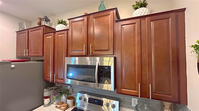 kitchen featuring appliances with stainless steel finishes, dark countertops, brown cabinets, and decorative backsplash