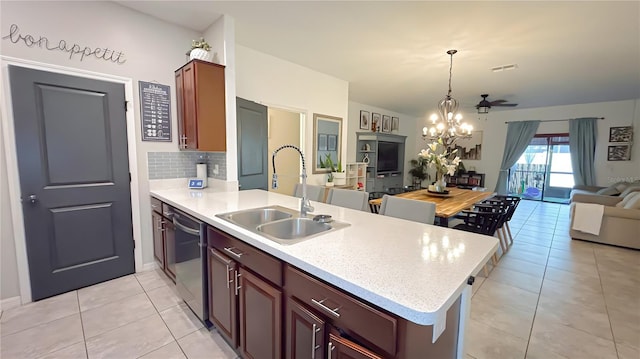 kitchen featuring decorative light fixtures, light countertops, open floor plan, a sink, and dishwashing machine