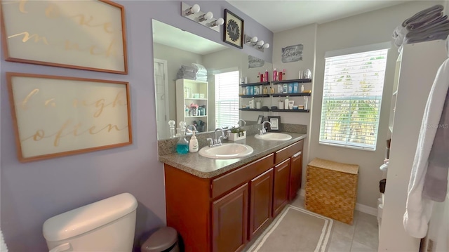 full bathroom featuring double vanity, toilet, a sink, and tile patterned floors