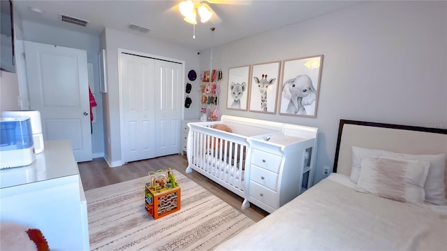 bedroom featuring ceiling fan, visible vents, dark wood-type flooring, and a closet