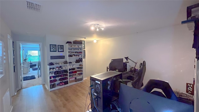 home office with light wood-type flooring and visible vents