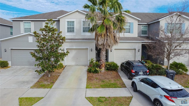 view of front of home with driveway, roof with shingles, a garage, and stucco siding