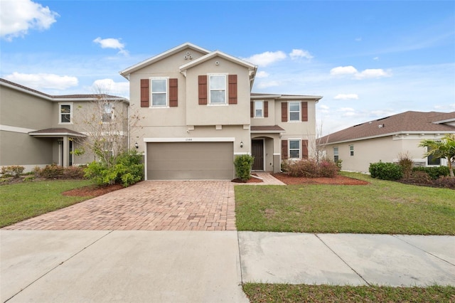 view of front of property with a front yard, decorative driveway, an attached garage, and stucco siding