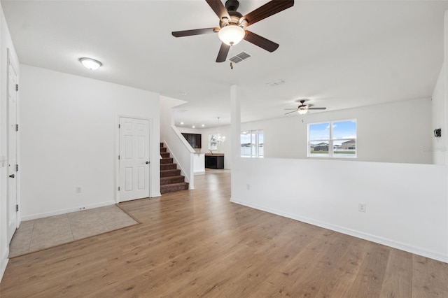 unfurnished room with light wood-type flooring, baseboards, stairs, and visible vents