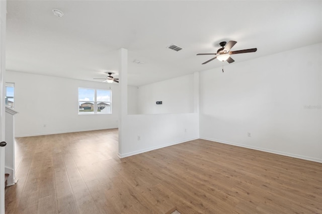 unfurnished room featuring a ceiling fan, baseboards, visible vents, and wood finished floors