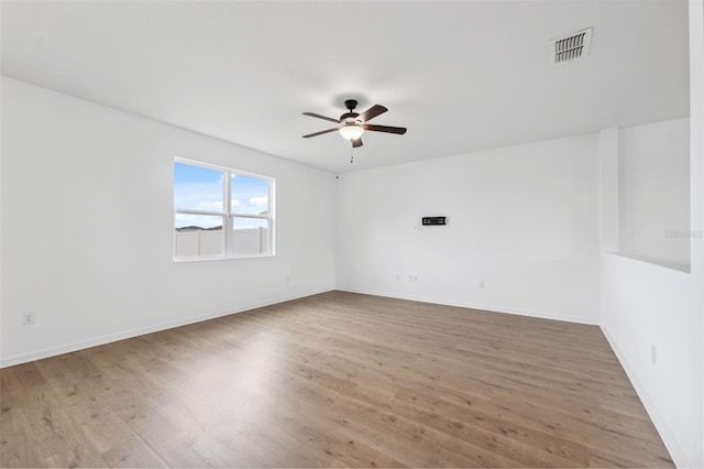 spare room featuring ceiling fan, wood finished floors, visible vents, and baseboards