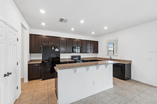 kitchen featuring dark brown cabinetry, visible vents, a breakfast bar area, a center island, and black appliances