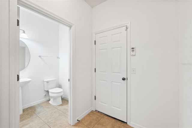 bathroom featuring tile patterned flooring, baseboards, and toilet