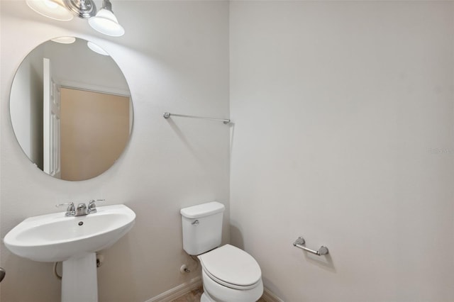 half bath with baseboards and toilet