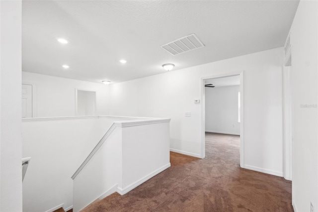 hallway featuring visible vents, baseboards, carpet, an upstairs landing, and recessed lighting