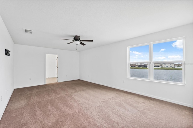 carpeted spare room featuring ceiling fan, a textured ceiling, visible vents, and baseboards