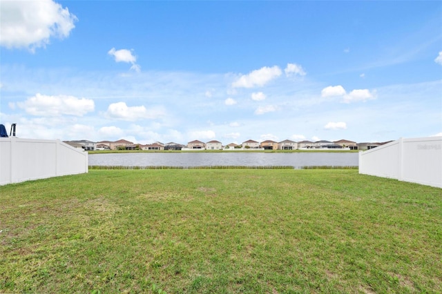 view of yard with a water view, a residential view, and fence