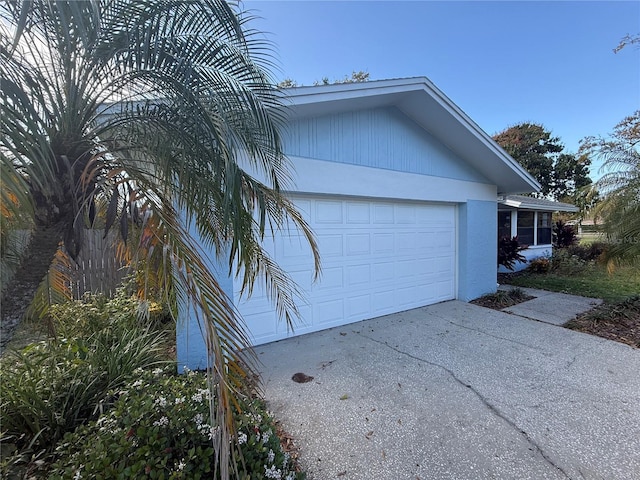 view of property exterior with an attached garage, driveway, and stucco siding