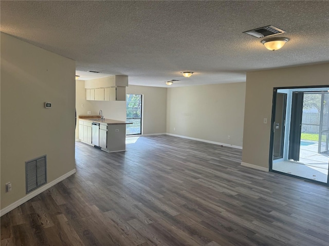 unfurnished living room with a wealth of natural light, visible vents, and dark wood finished floors