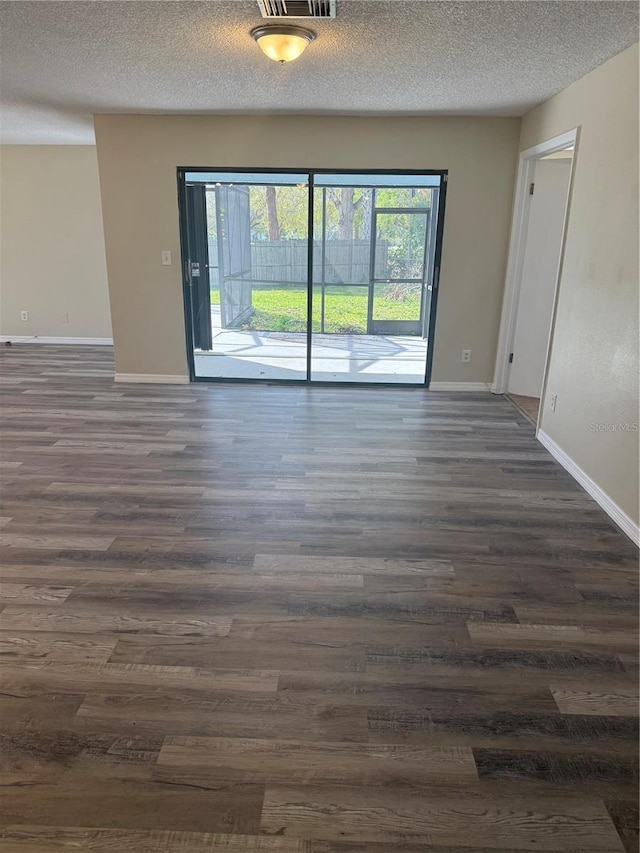 unfurnished room with dark wood-type flooring, baseboards, visible vents, and a textured ceiling